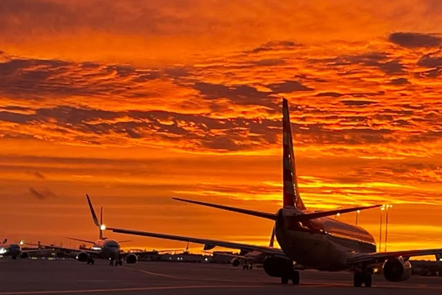 Aeronaves en la plataforma del Aeropuerto Internacional de Miami bajo un atardecer rojo y naranja, fotografiadas por la escuela